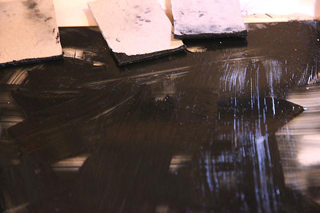 A smooth surface covered in smears of wet black ink.