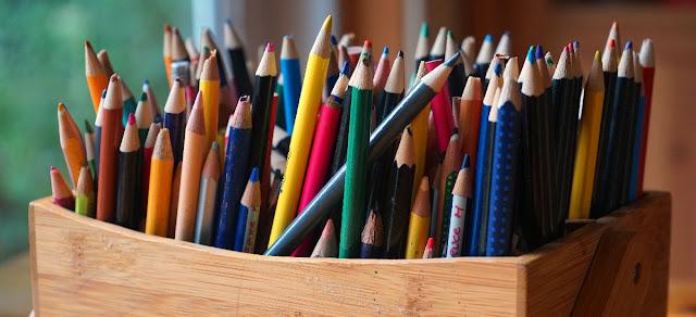 A close-up view of a wooden box filled with a large assortment of coloured pencils.