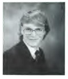 A very low-resolution black-and-white image of 18-year-old Markus, with a mop of blond hair, a wide smile, and square-rimmed glasses. He is wearing a white collared shirt with a dark tie and blazer. It's a classic yearbook photo.