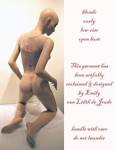 A mannequin wears a thong and transparent nylon top that match its pale skin-tone. Both the top and bottom have tags that say: Lovely Bush, Aesthetic Prosthetics for the Aspiring Woman. The side of the image (which is a marketing tag) says: blonde, curly, low-rise, open bust. This garment has been artfully reclaimed and designed by Emily van Lidth de Jeude. Handle with care. Do not launder.
